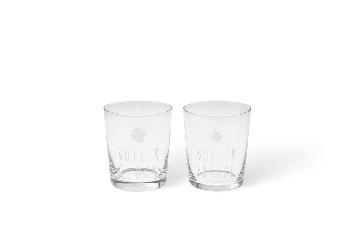 Zwei transparente Trinkgläser mit Blüten- und Sonnenmotiv sowie den Aufschriften, Voller Glück und Voller Freude, in der Vorderansicht.